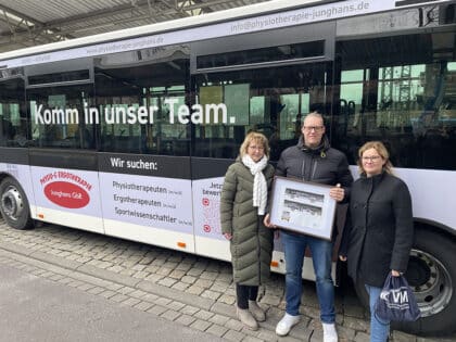 Drei Personen stehen vor einem weißen Bus Am Zentralen Omnibus Bahnhof