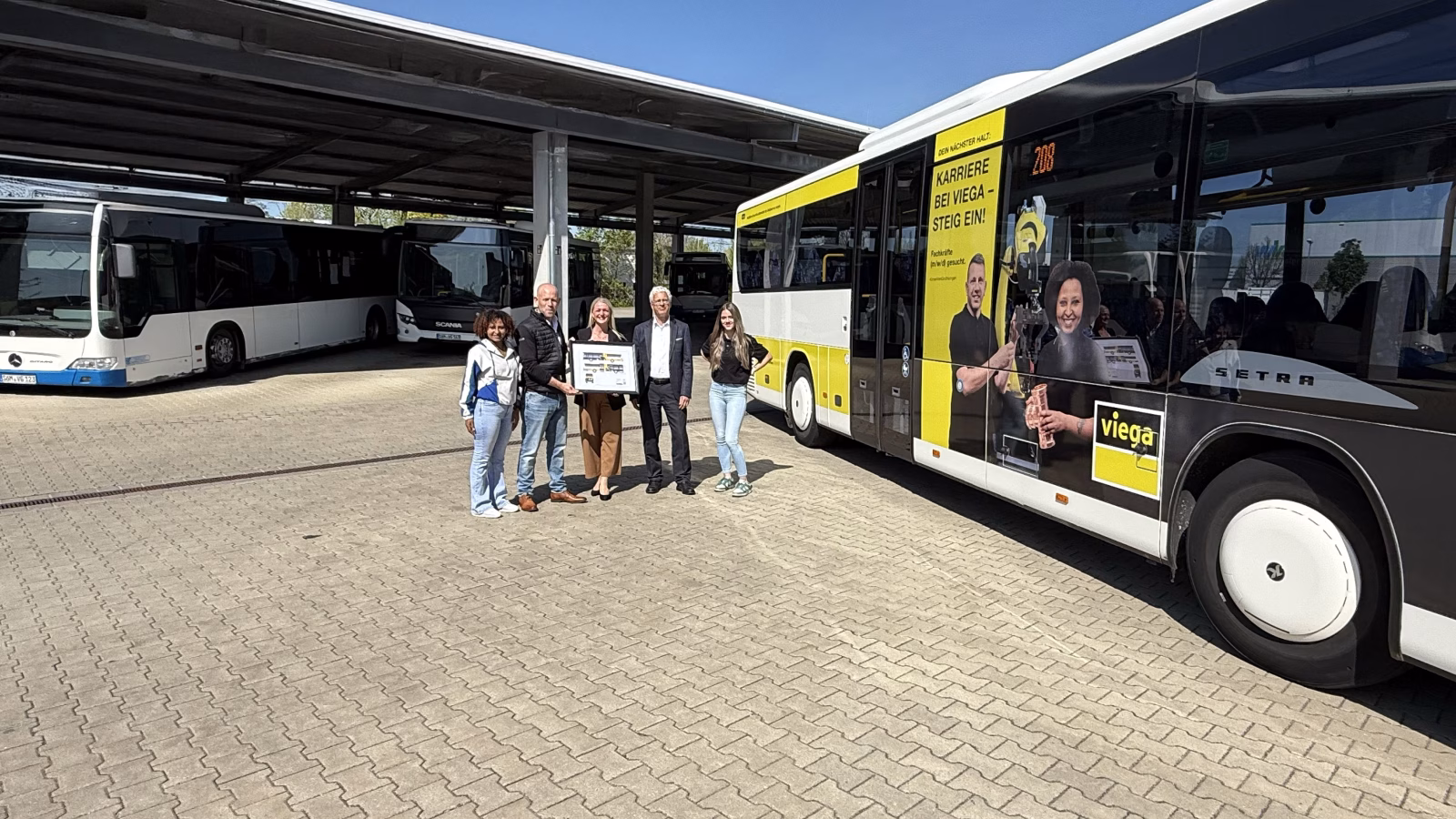 vier Personen stehen vor einem Bus, der Werbung für Azubis macht 