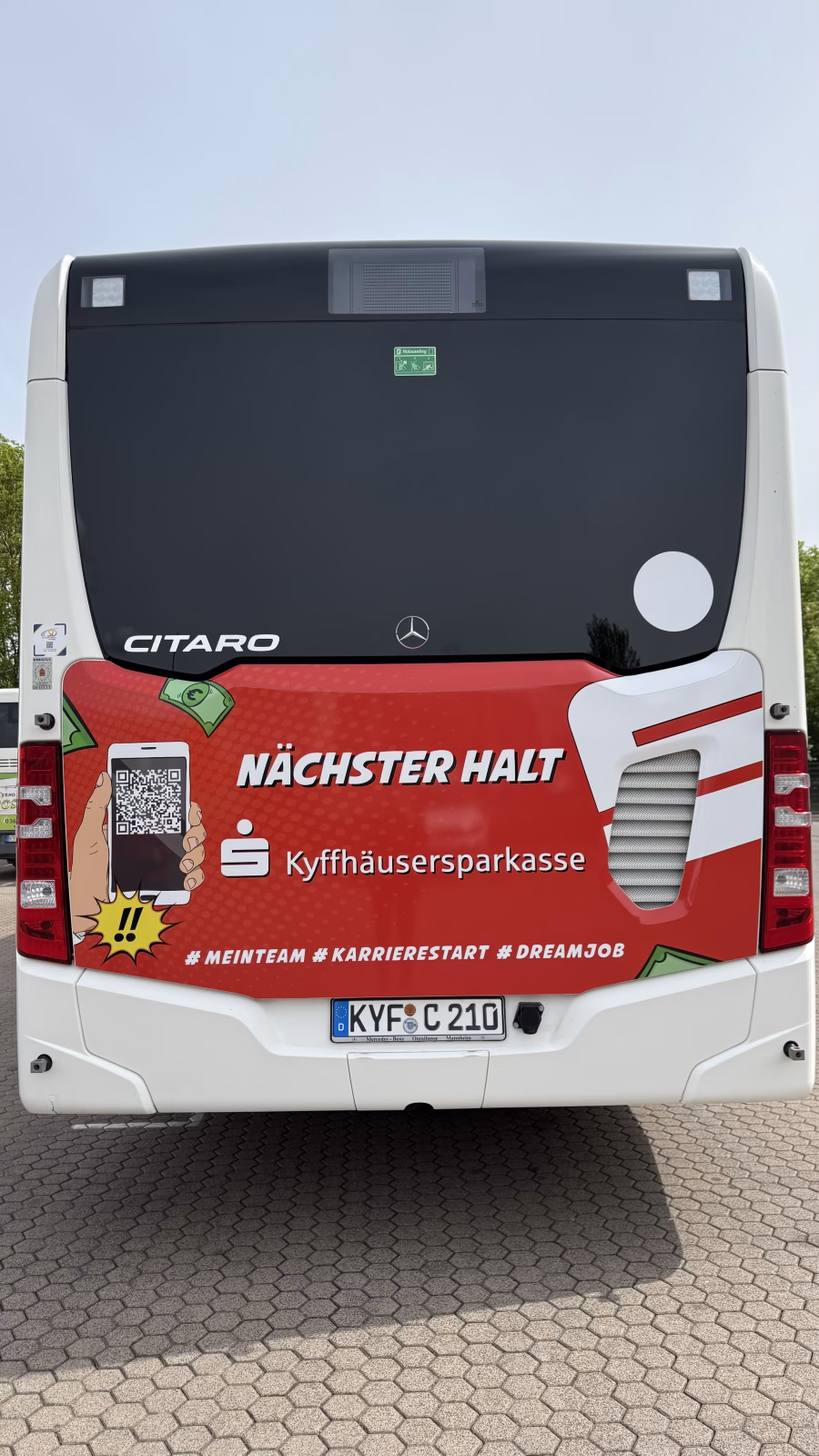 Heckansicht eines roten Busses, der Werbung für die Kyffhäusersparkasse macht 
