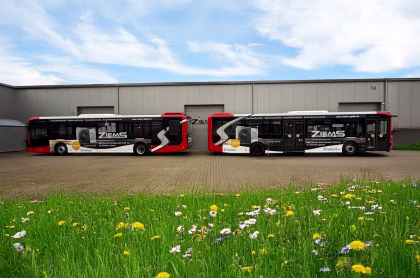 Zwei Busse stehen vor einem großen Werksgebäude