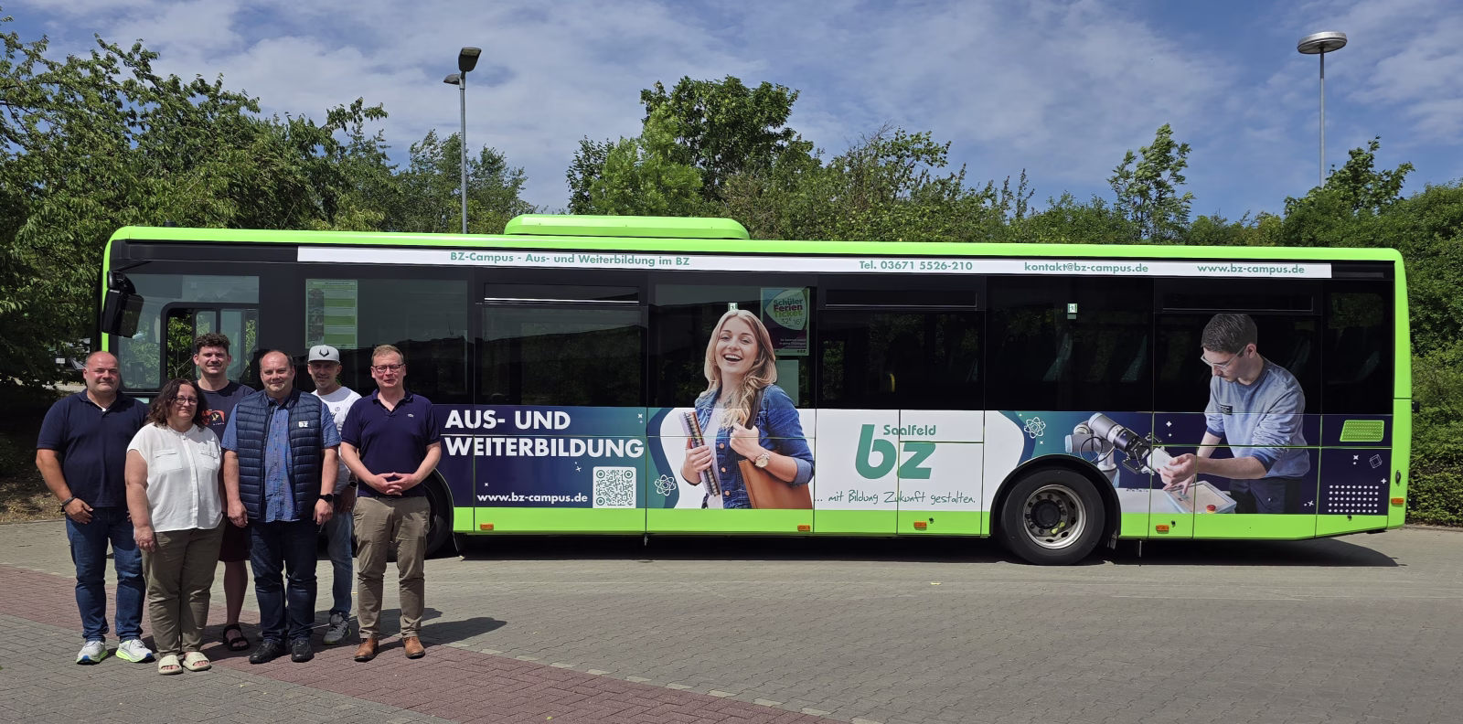 Eine Gruppe von Menschen steht vor einem grünen Werbebus des Bildungszentrums Saalfeld