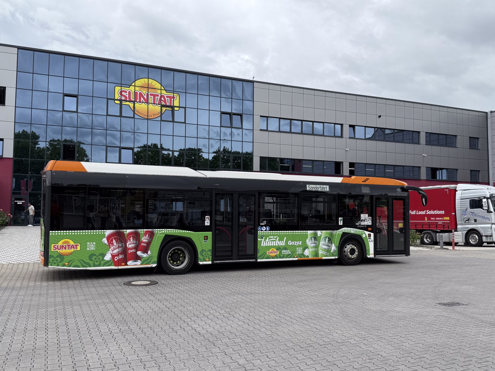 Einstiegsseite eines grünen Busses mit Werbung der Firma Suntat