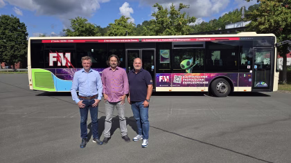 Drei Männer stehen vor einem Bus der FM Elektrotechnik