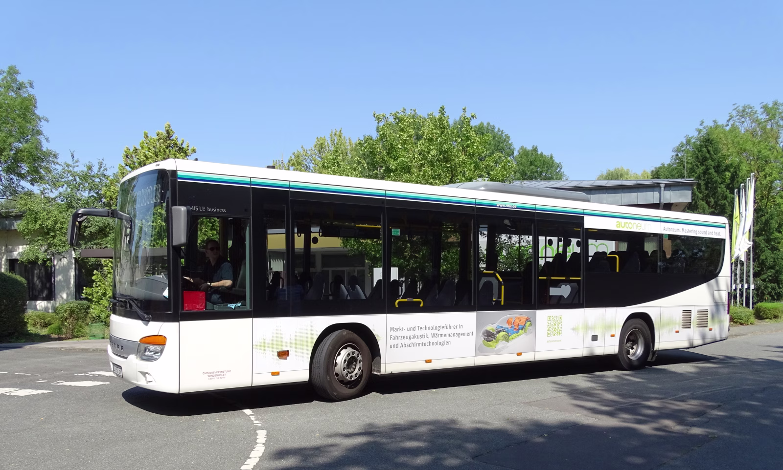 Seitenansicht eines weißen Busses der Firma Autoneum Germany GmbH