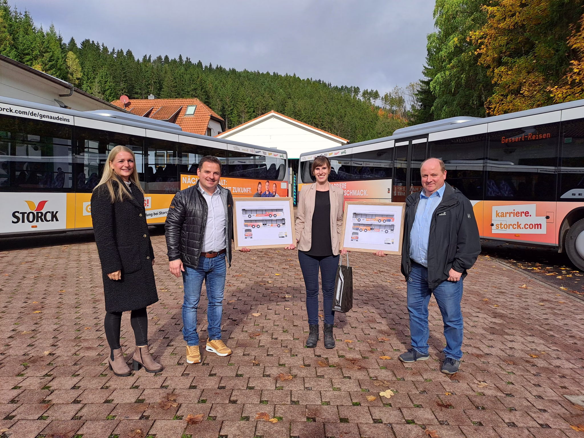 Vier Personen stehen vor zwei Bussen der Firma Storck