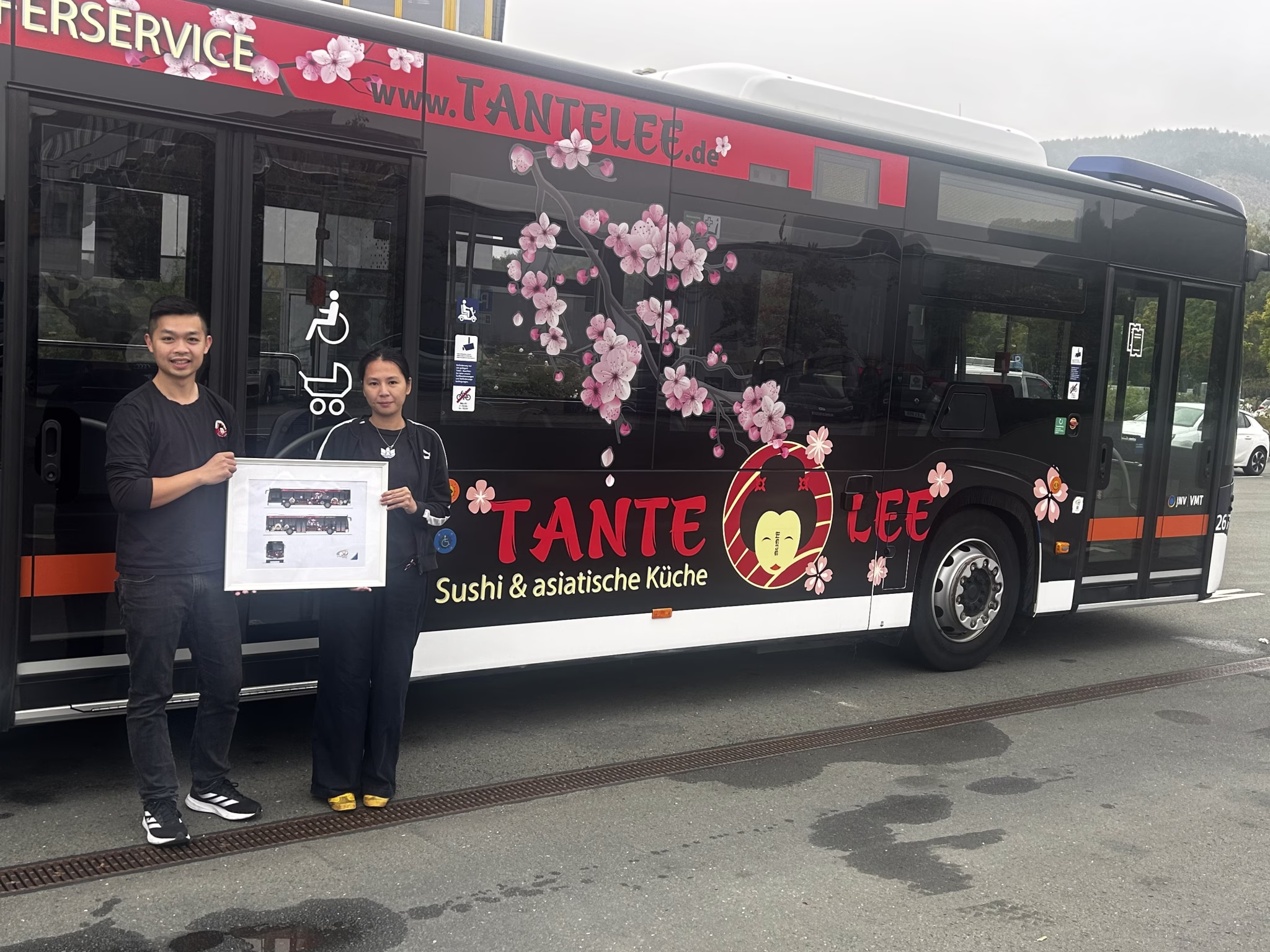 Zwei Personen stehen vor einem Werbebus des Unternehmens Tante Lee