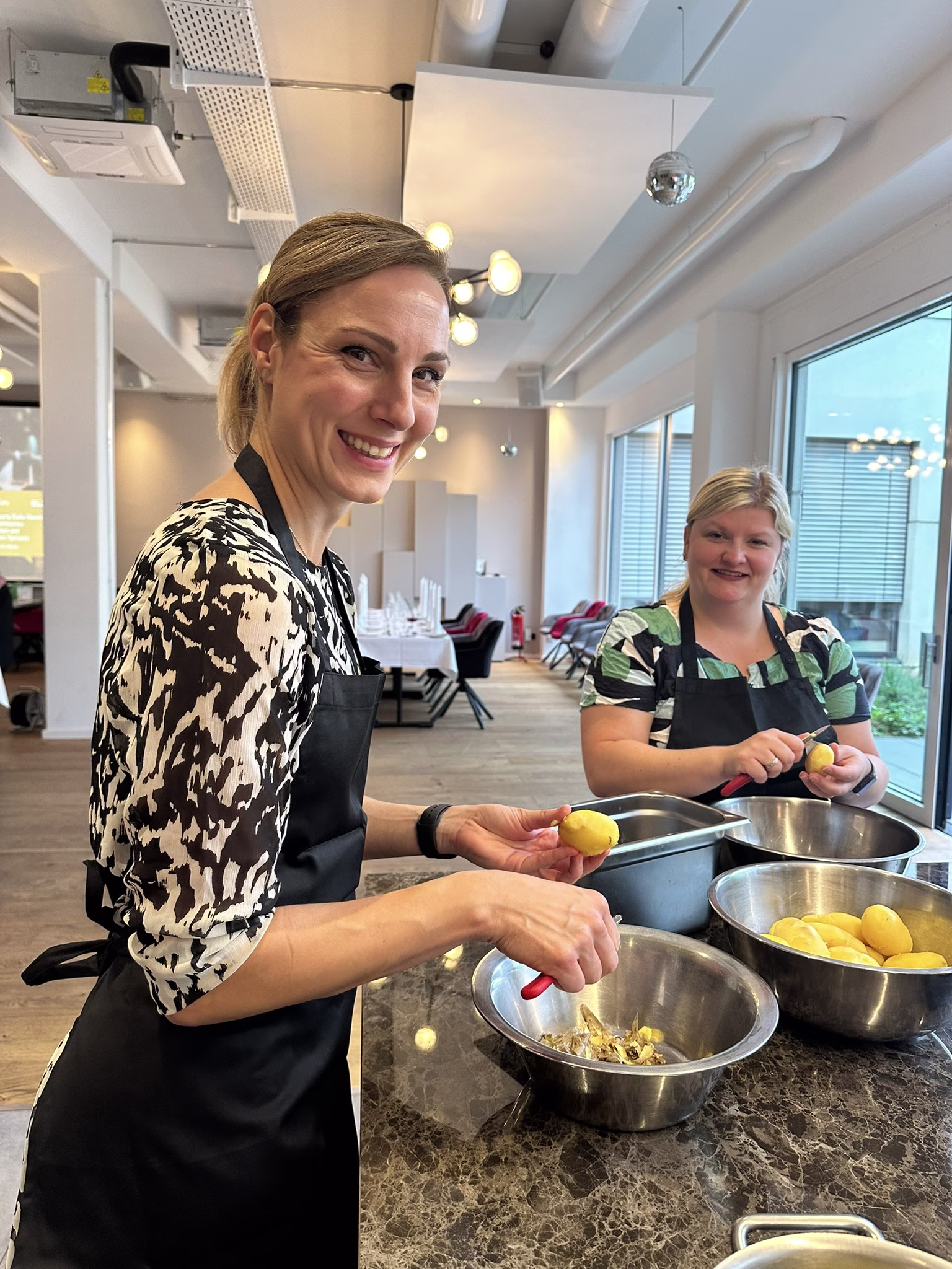 Zwei Personen schälen Kartoffeln und lachen in die Kamera