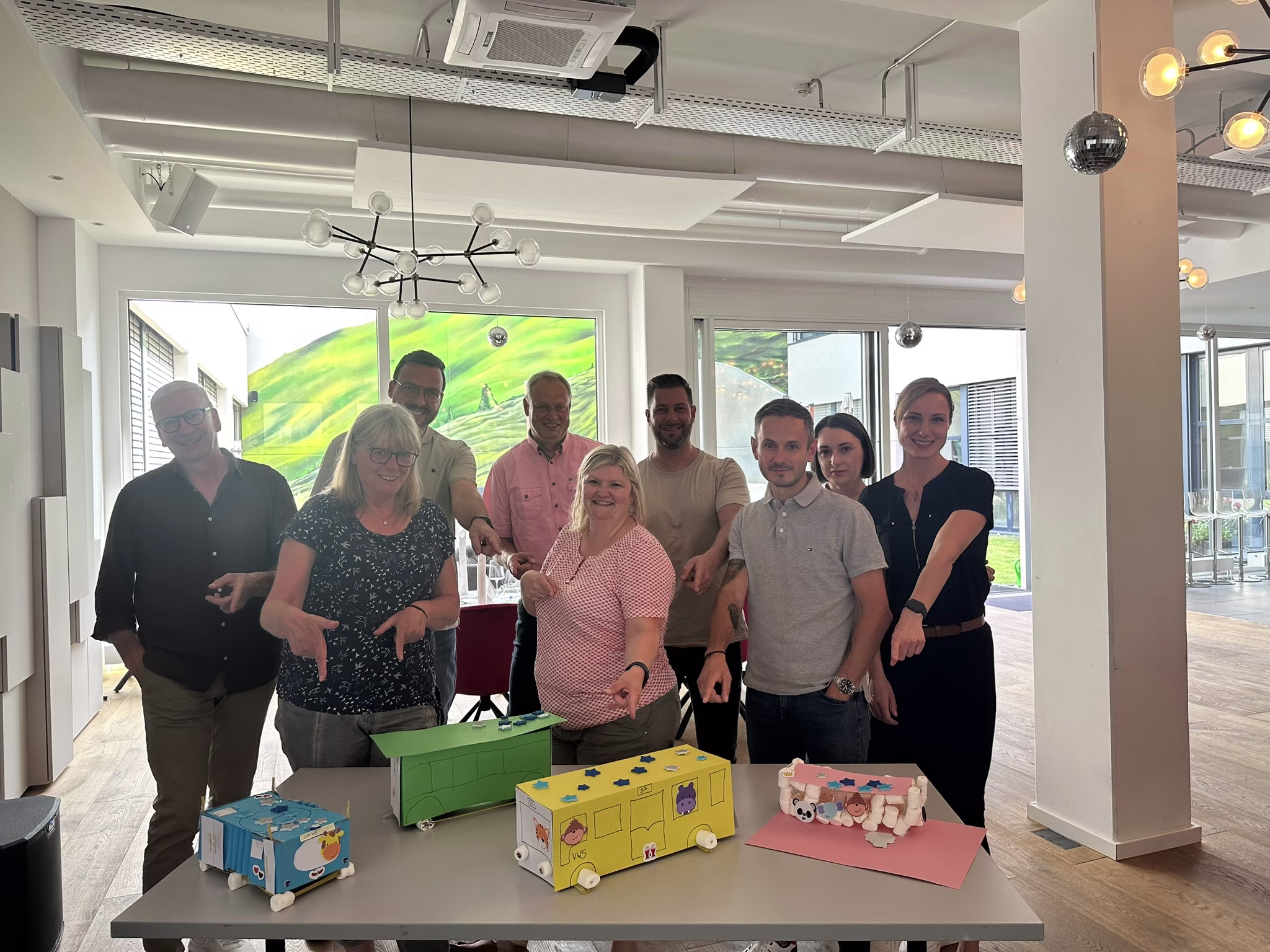 Eine Gruppe steht vor einem Tisch und zeigt auf selbstgebastelte Busse