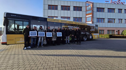 Eine Gruppe von Menschen steht vor einem Bus mit Plakaten des Busses