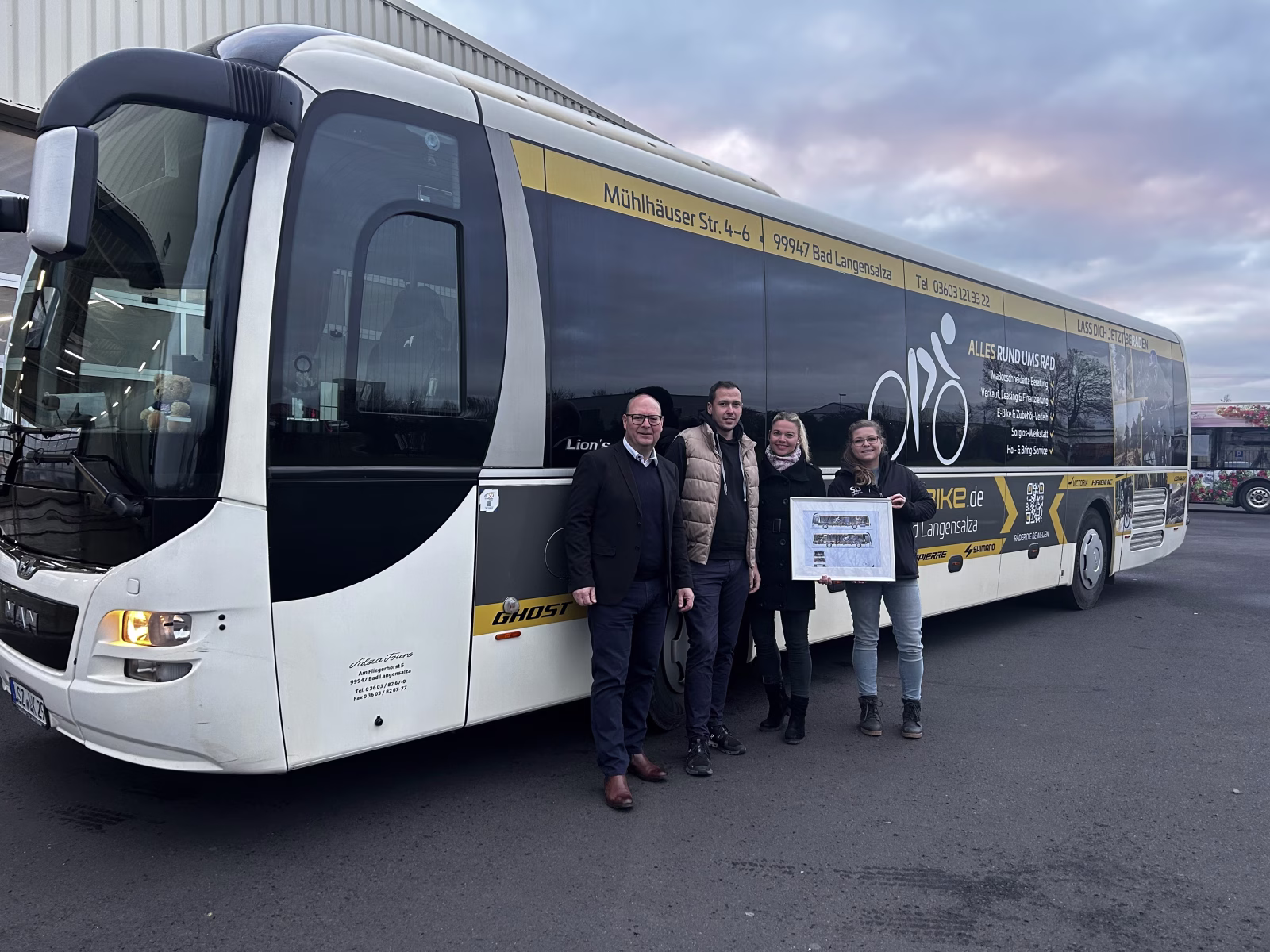 Vier Personen stehen vor einem Bus mit Werbung von Salza Bikes