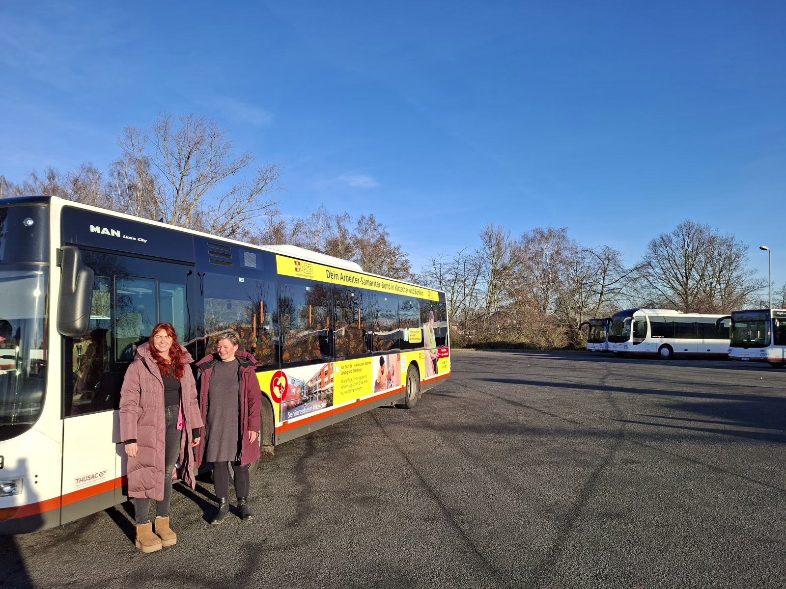 Zwei Frauen stehen vor einem Bus mit Werbung der ASB