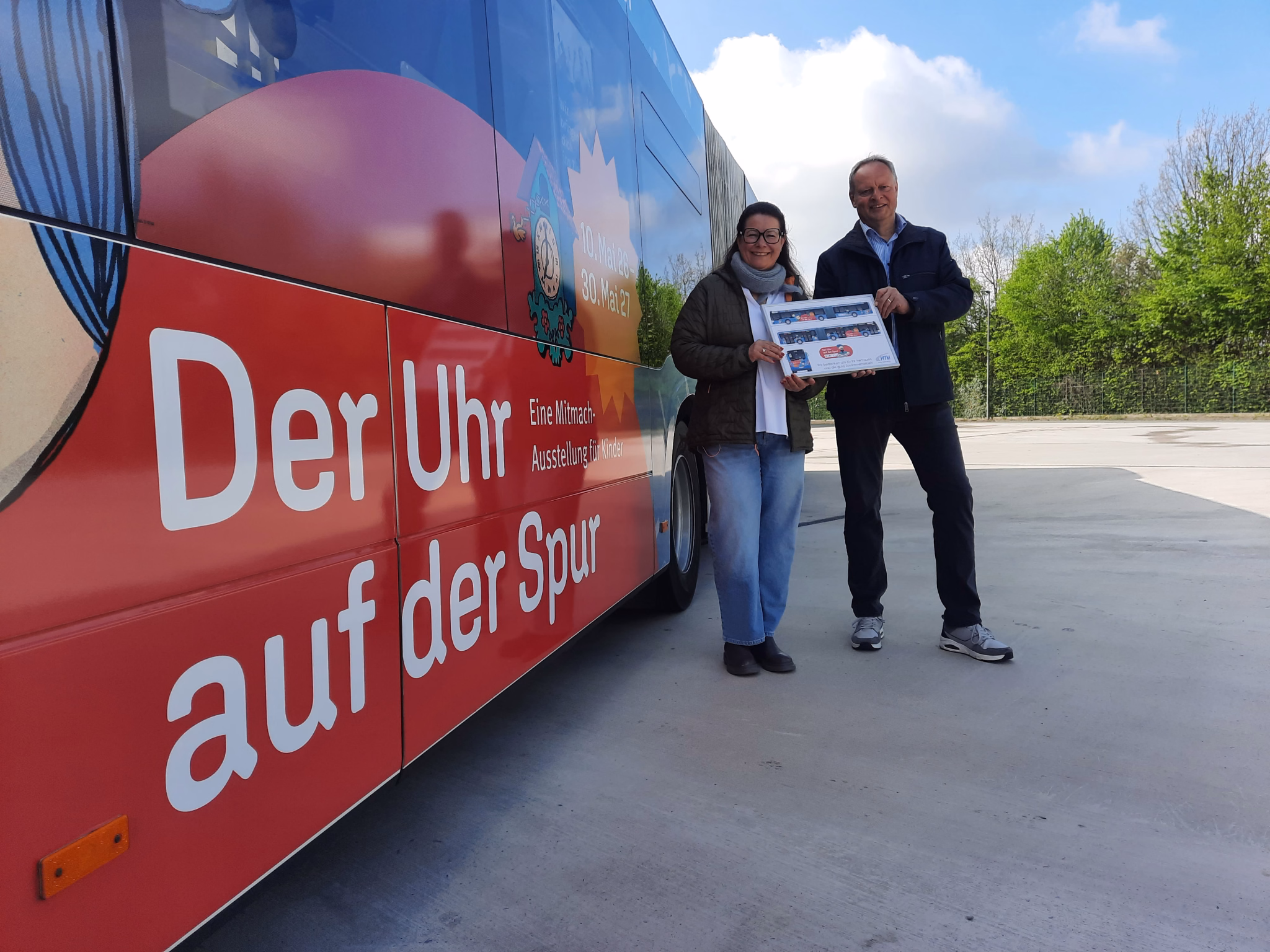 Zwei Personen stehen vor einem Bus mit Werbung des Heinz Nixdorf MuseumsForum