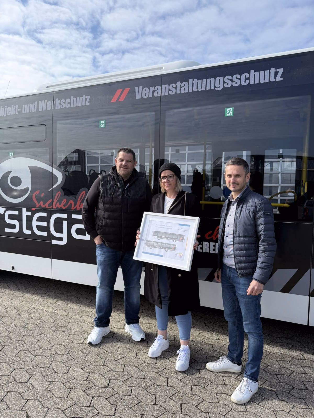 Drei Personen stehen vor dem Werbebus der Firma Stega