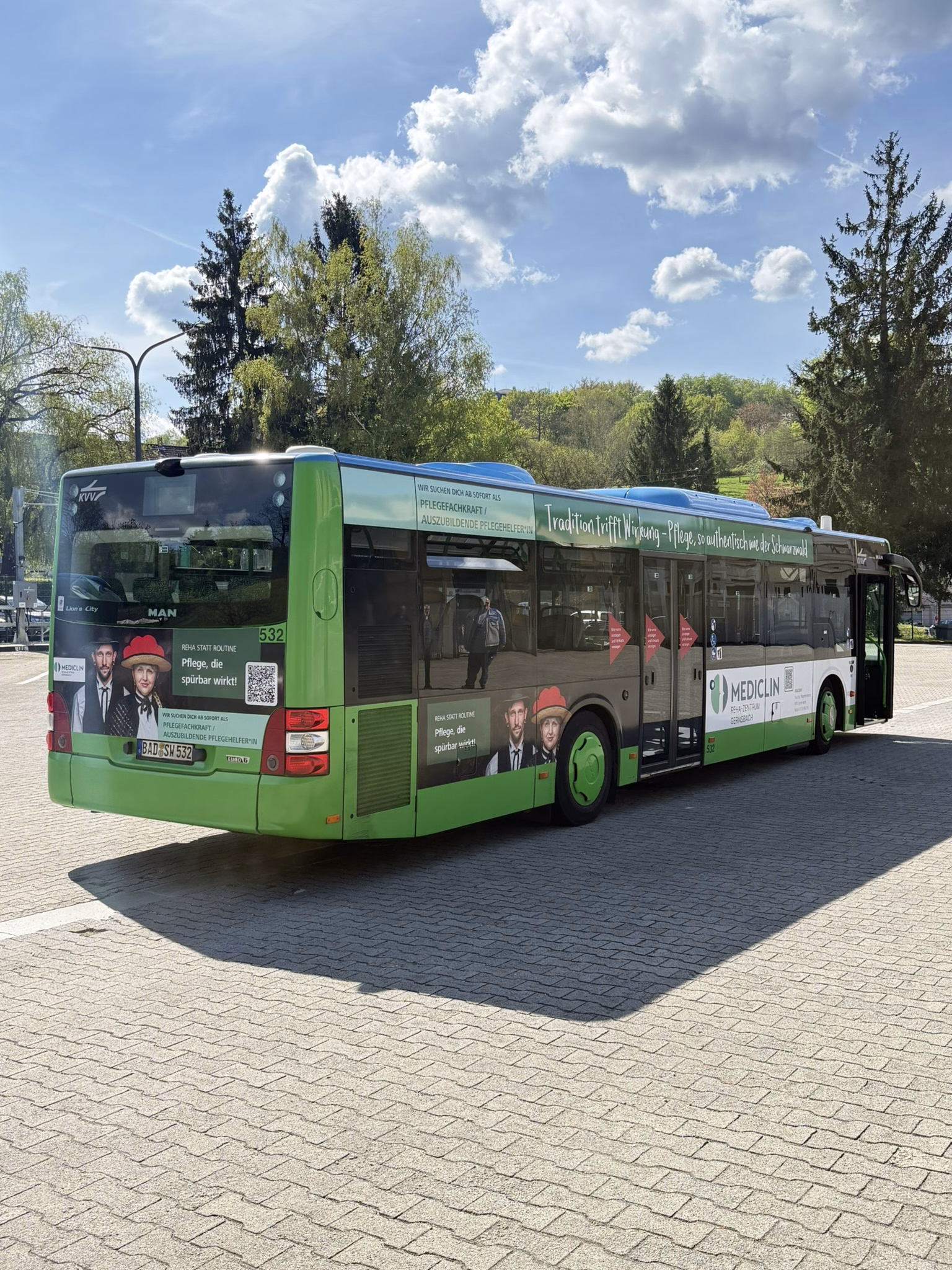 Heck- und Einstiegsseite eines grünen Busses mit Werbung der Mediclin Gernsbach