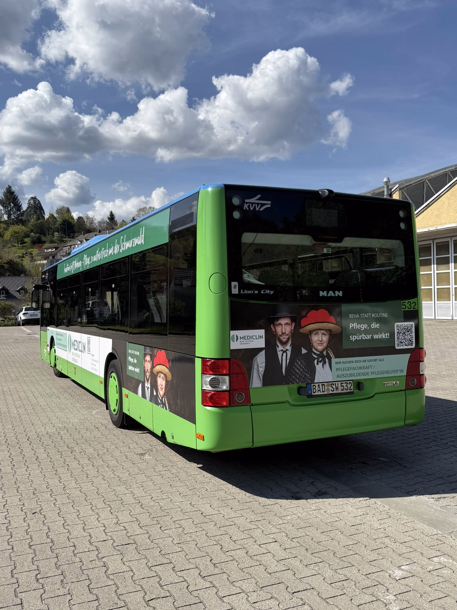 Heck- und Seitenaufnahme eines grünen Busses mit Werbung des Mediclin Gernbach
