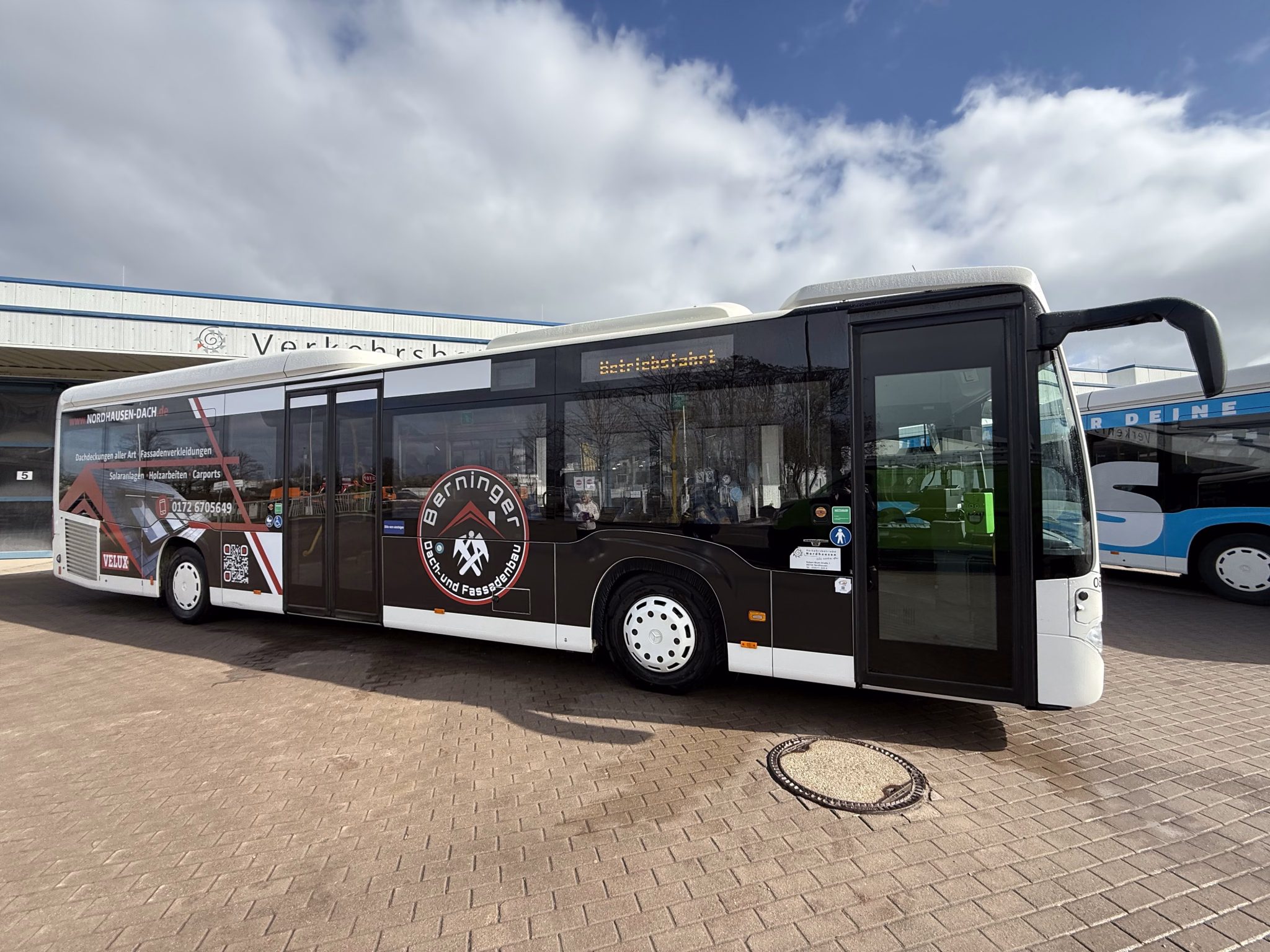 Einstiegsseite eines Busses mit Werbung des Dach- und Fassadenbaus Berninger
