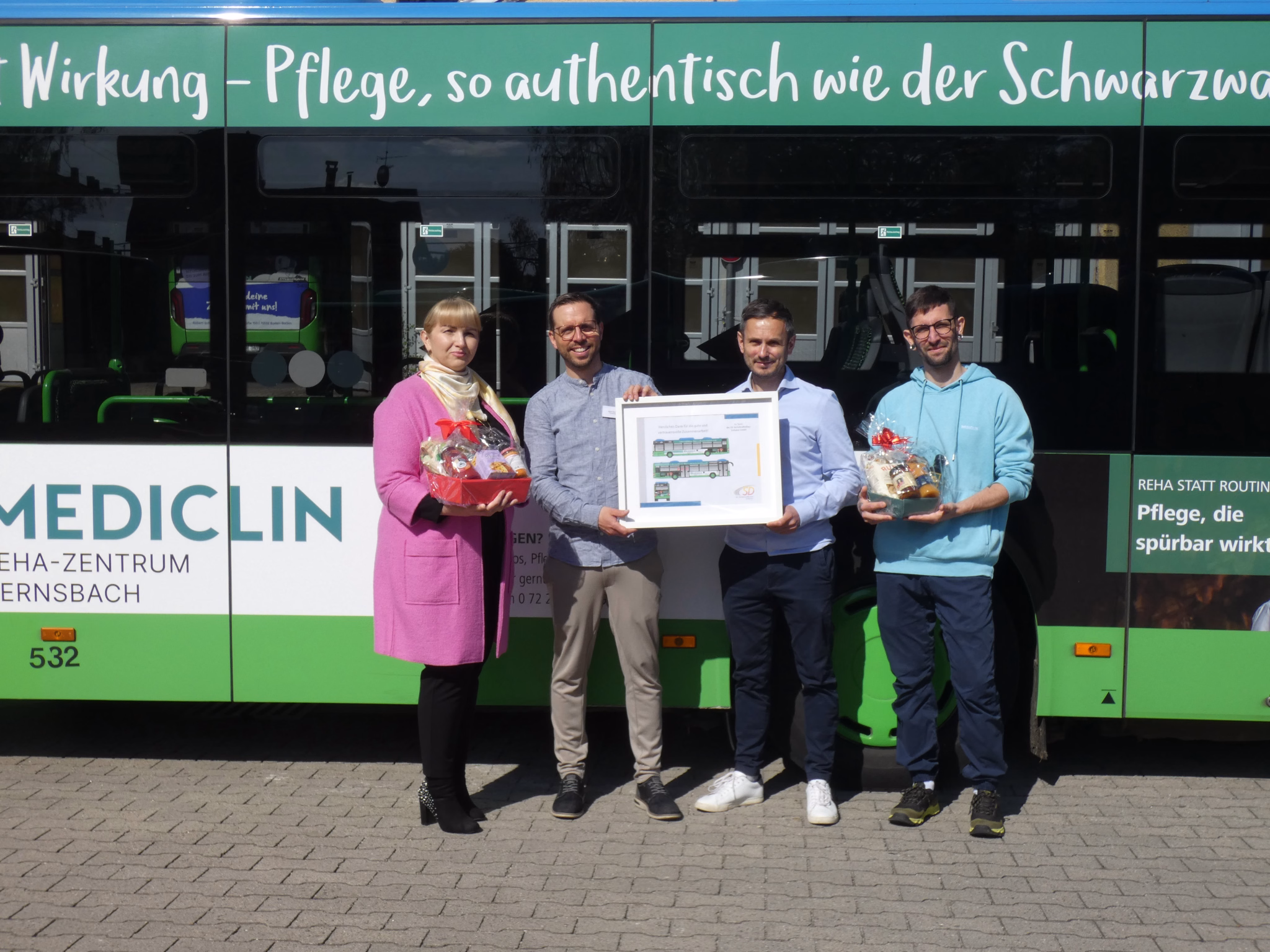 Vier Personen stehen vor einem grünen Bus mit Werbung von Mediclin