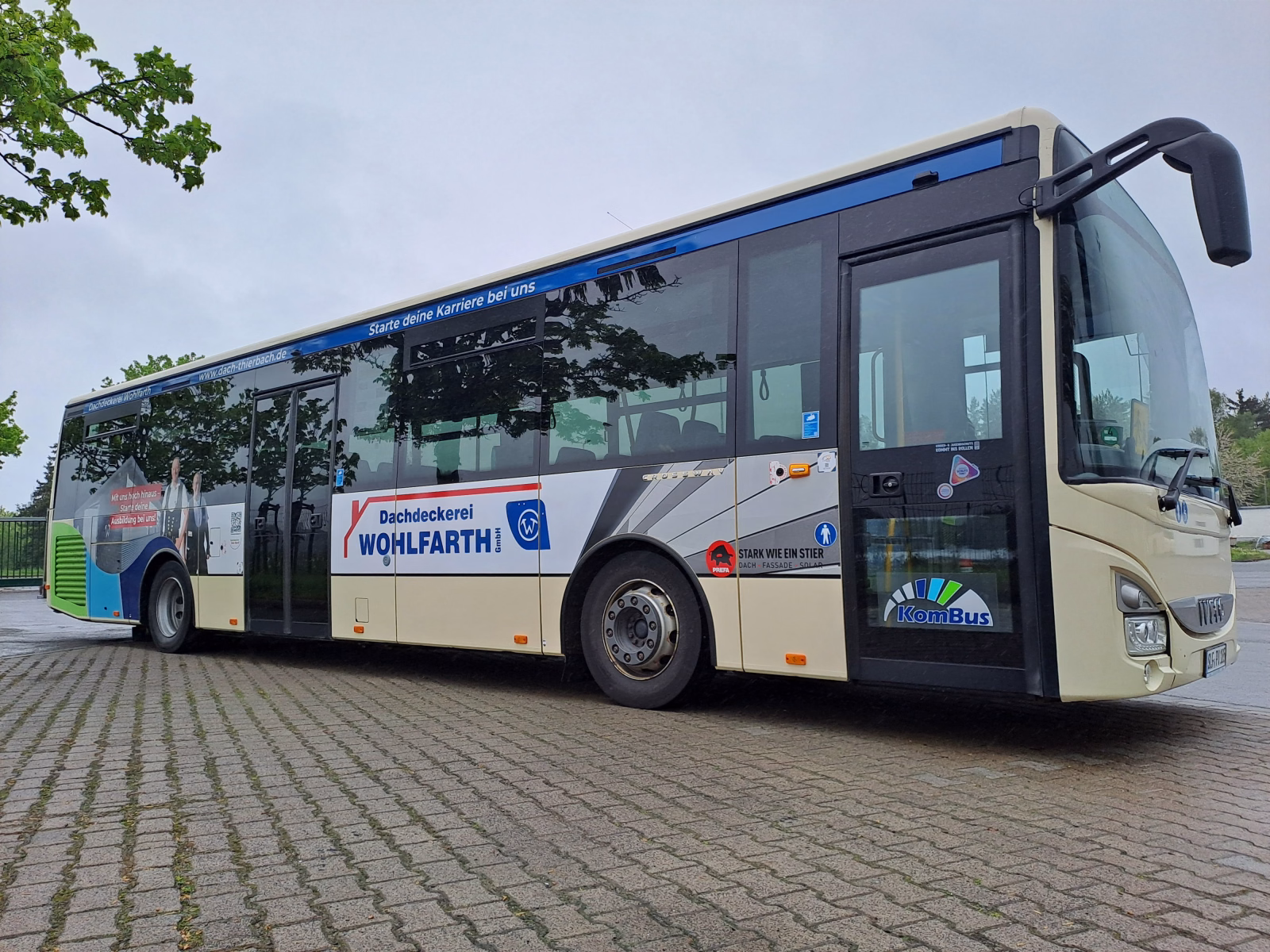 Einstiegsseite eines beigen Werbebusses mit Werbung der Dachdeckerei Wohlfarth