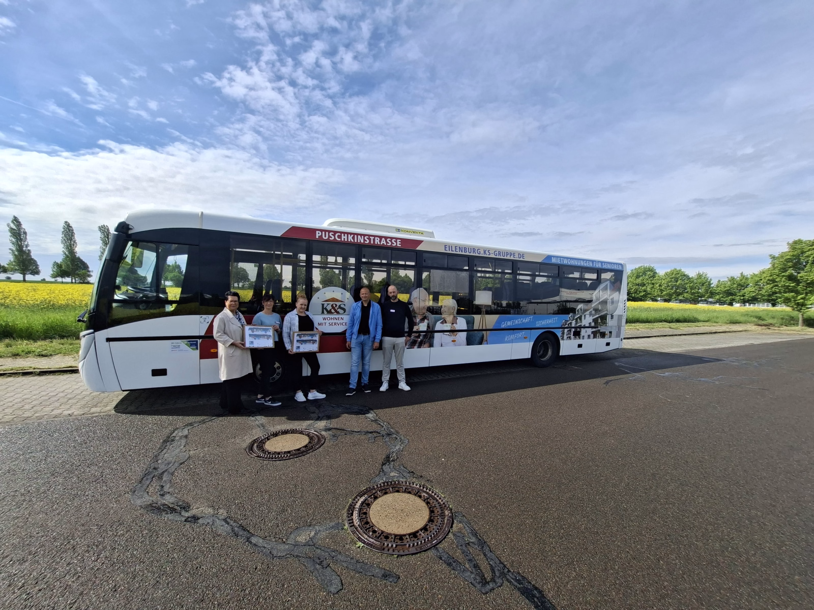 Fünf Personen stehen vor einem Bus mit einer Ganzwagenwerbung der K&S Seniorenresidenz Eilenburg