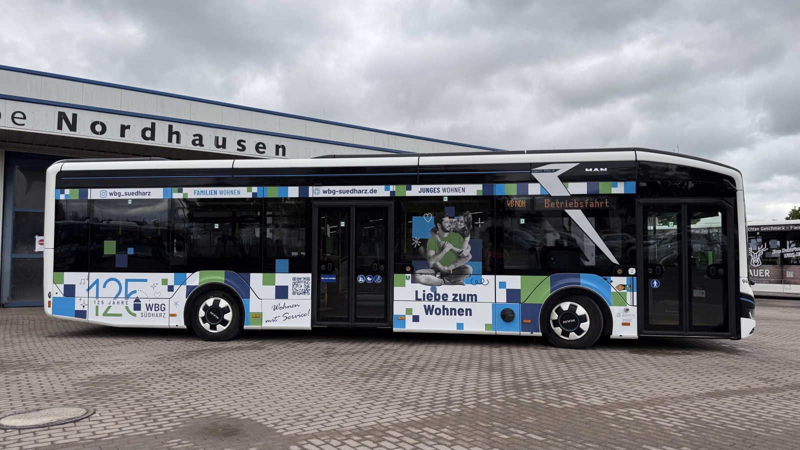 Seitenansicht eines weißen Werbebusses, der auf einem Betriebshof steht mit Werbung der WBG Südharz