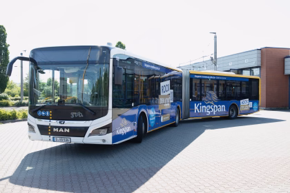 Seitenansicht eines blauen Gelenkbusses mit Werbung von Kingspam