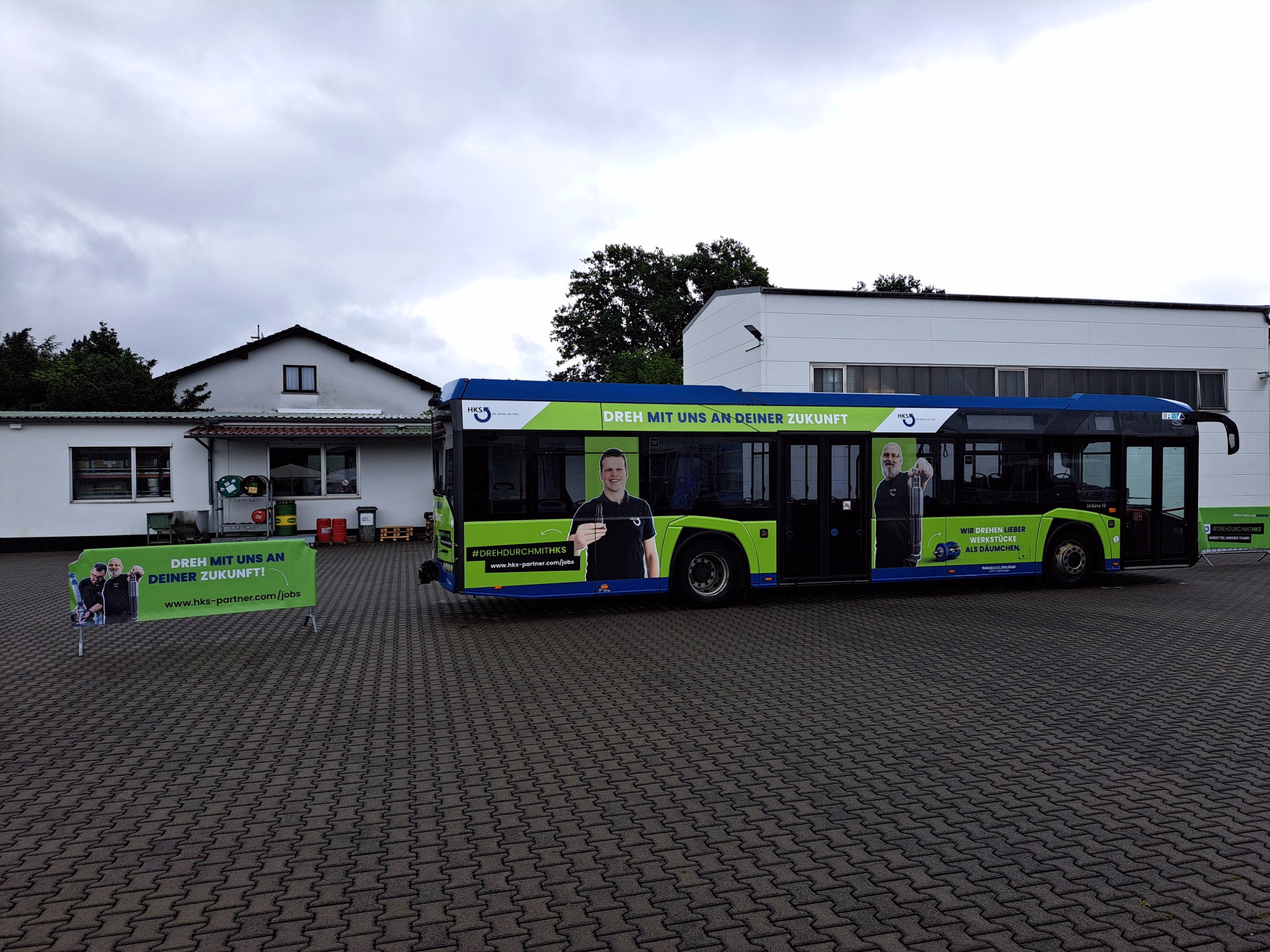 Einstiegsseite eines grünen Werbebusses mit Werbung der HKS Dreh-Antriebe GmbH