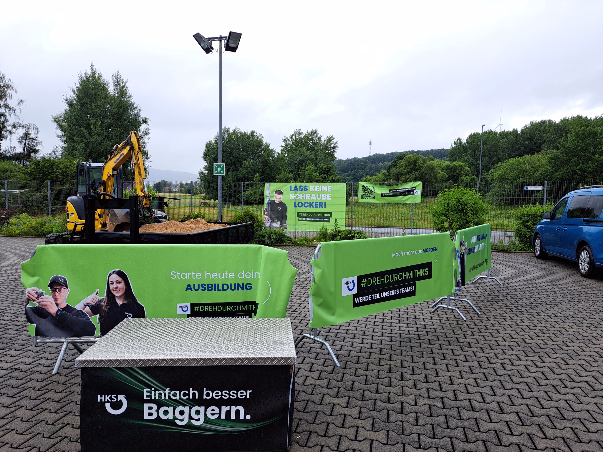 Ein gelber Bagger steht auf einem Parkplatz innerhalb einer kleinen Sandgrube