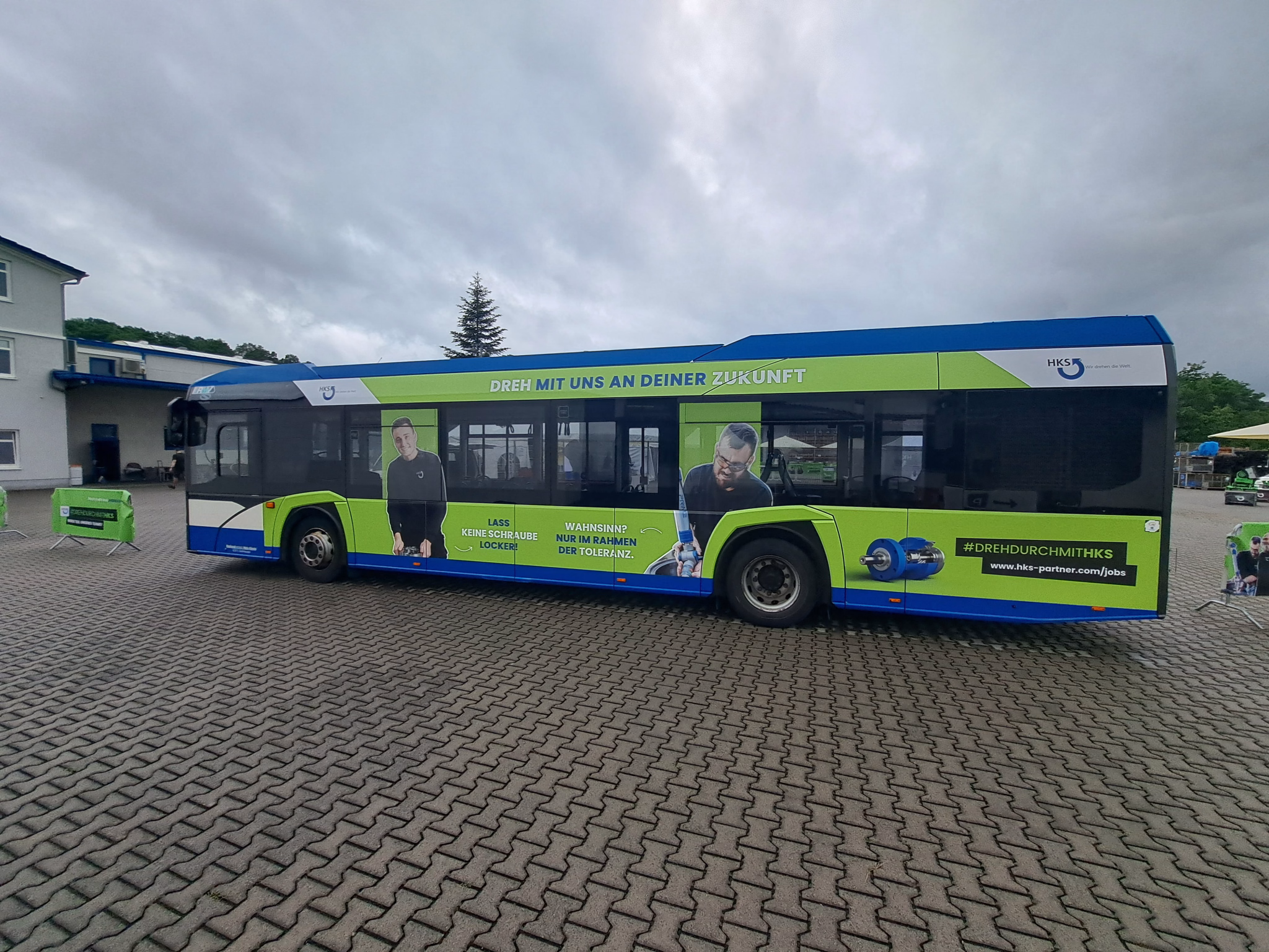 Außenseite eines grünen Werbebusses mit Werbung der HKS Dreh-Antriebe GmbH