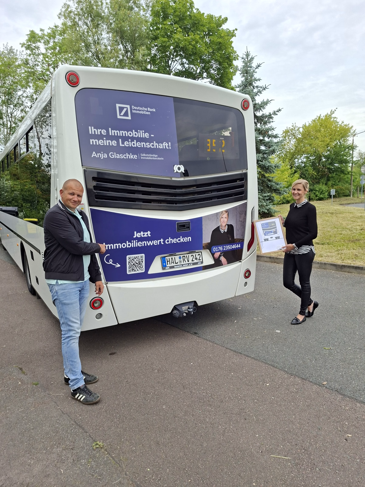 Zwei Personen stehen vor dem Heck eines weißen Busses