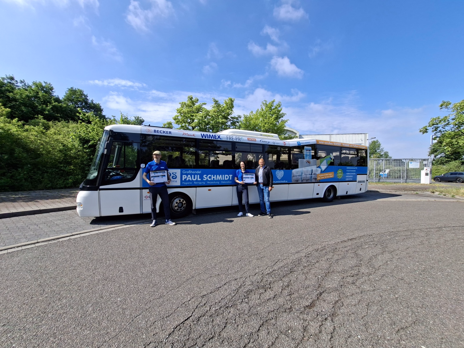 Drei Personen posieren mit einer Skizze vor dem entsprechenden Bus