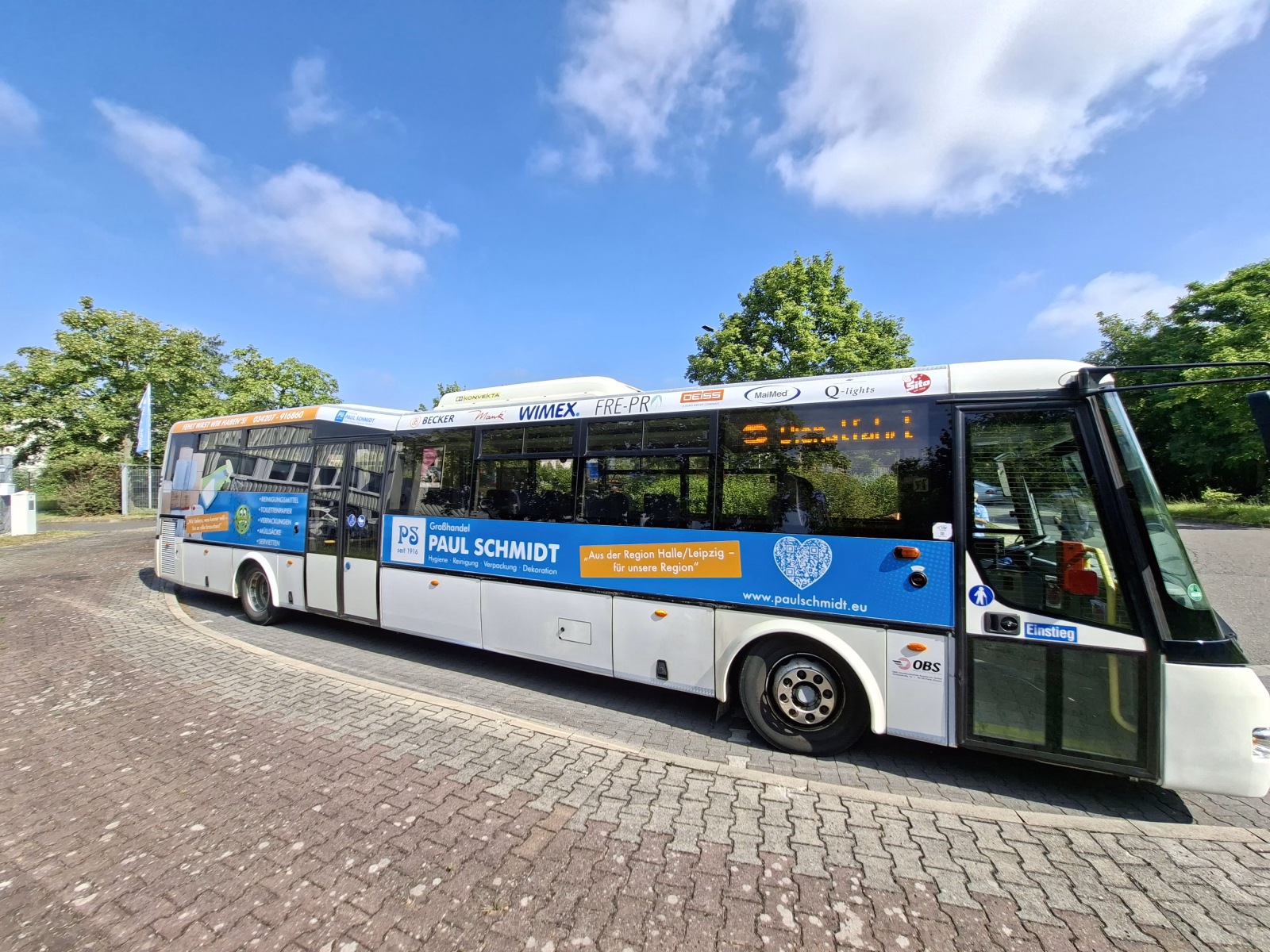 Einstiegsseite eines weiß/blauen Stadtbusses mit Werbung der Paul Schmidt Handels GmbH