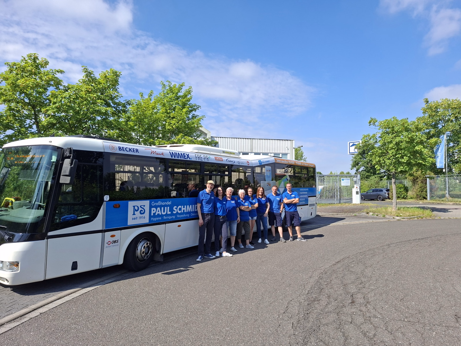 Eine Gruppe von Menschen steht vor einem weiß/blauen Stadtbus mit Werbung der Paul Schmidt Handels GmbH