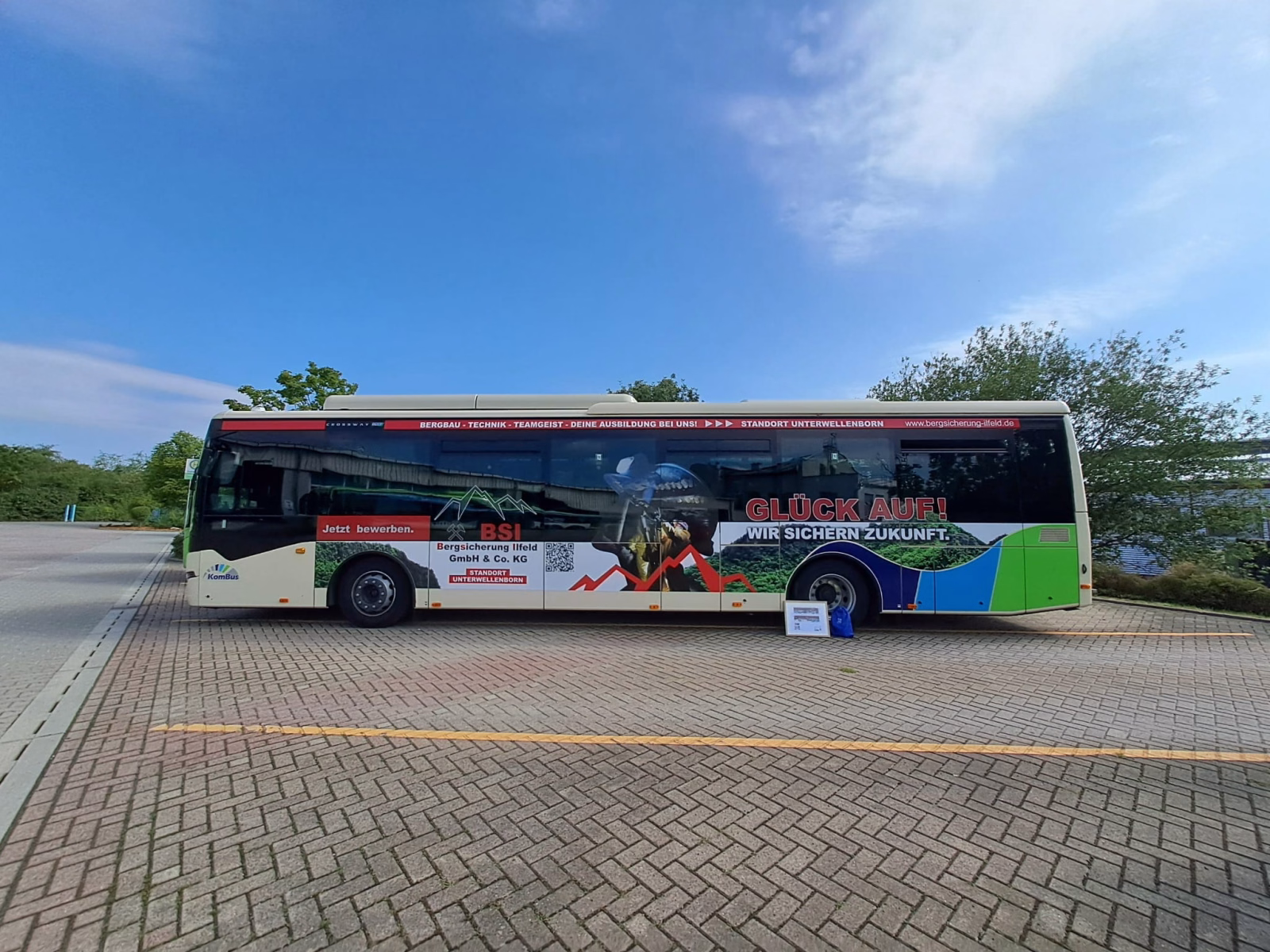 Außenseite eines beigen Stadtbusses mit Werbung der Bergsicherung Illfeld