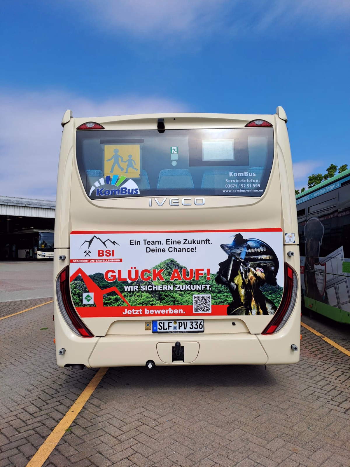 Heckansicht eines beigen Werbebusses mit Werbung der Bergsicherung Illfeld