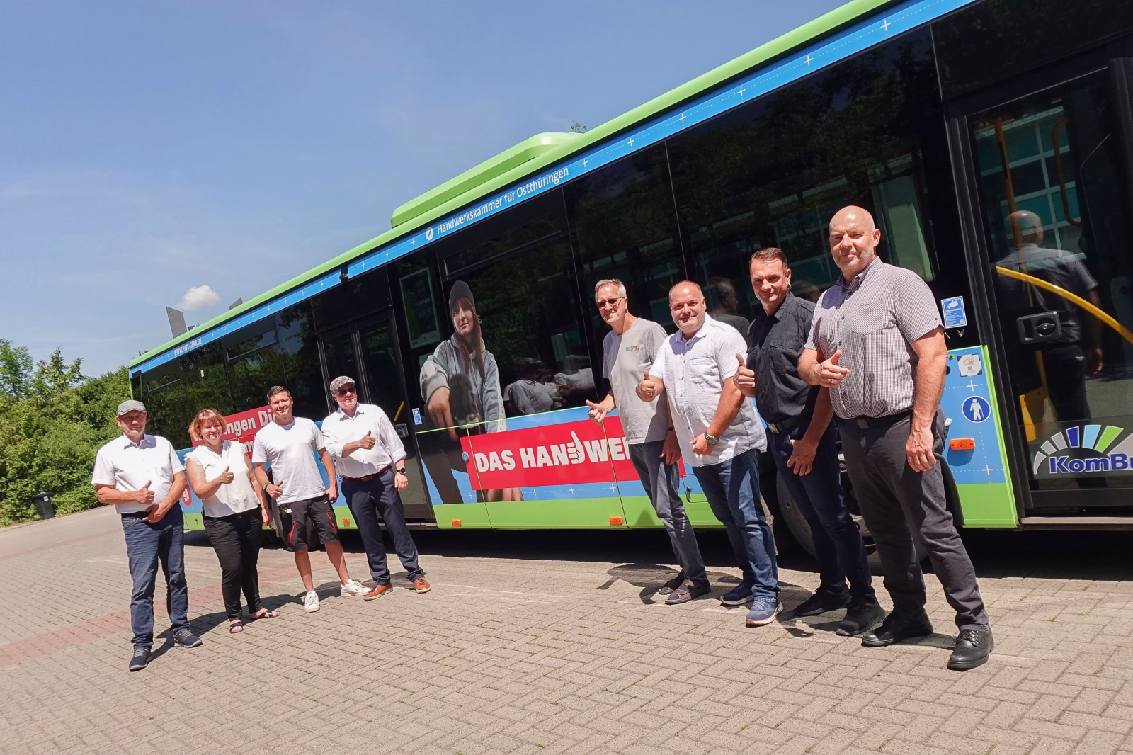 Eine Gruppe von Menschen steht auf einen Parkplatz vor einem bunten Bus der HWK Ostthüringen