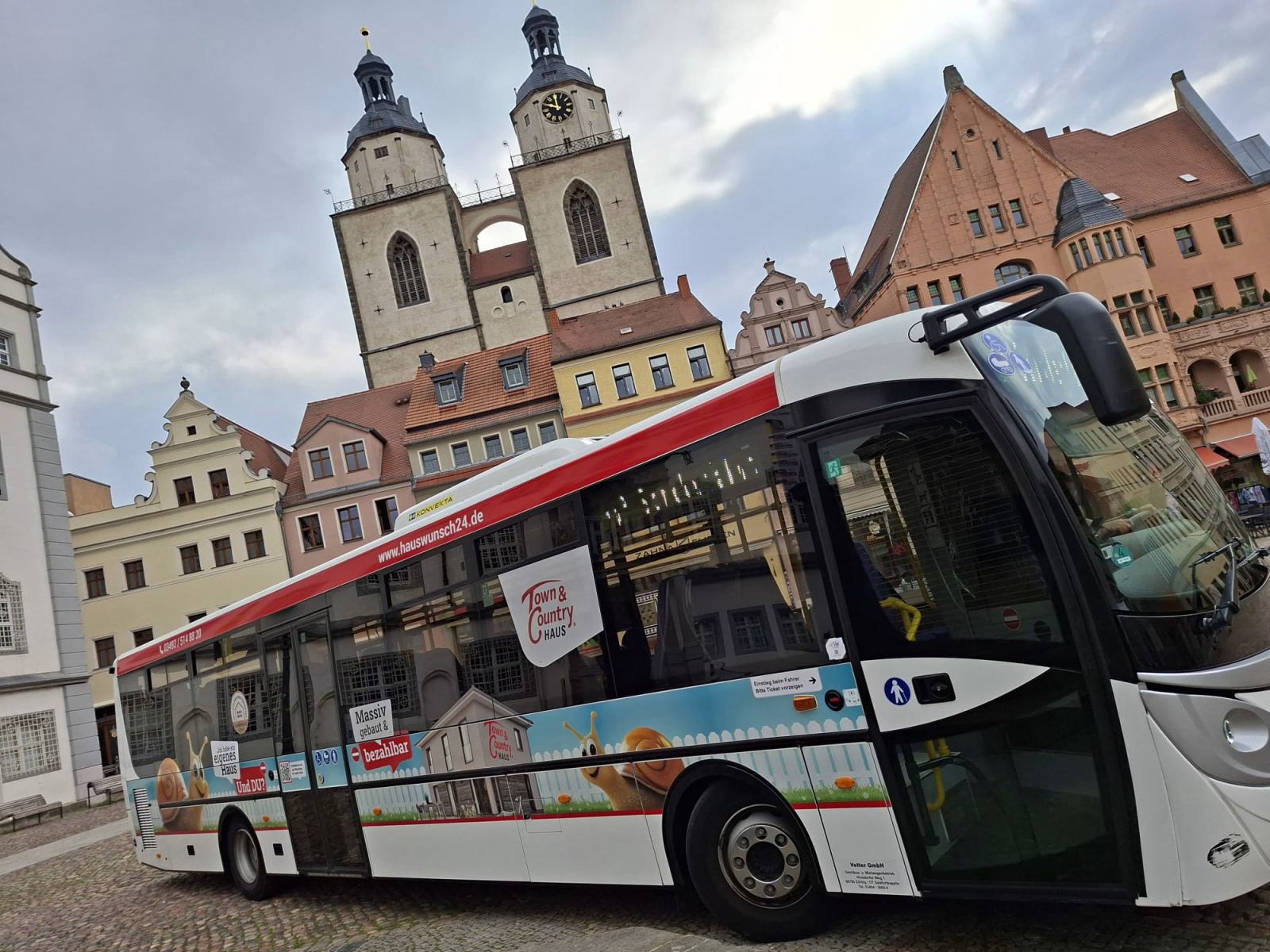 Einstiegsseite eines weißen Busses mit Werbung der HIS Hausbau GmbH