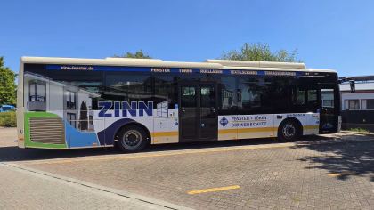 Einstiegsseite eines beigen Stadtbusses mit Werbung von Zinn Fenster