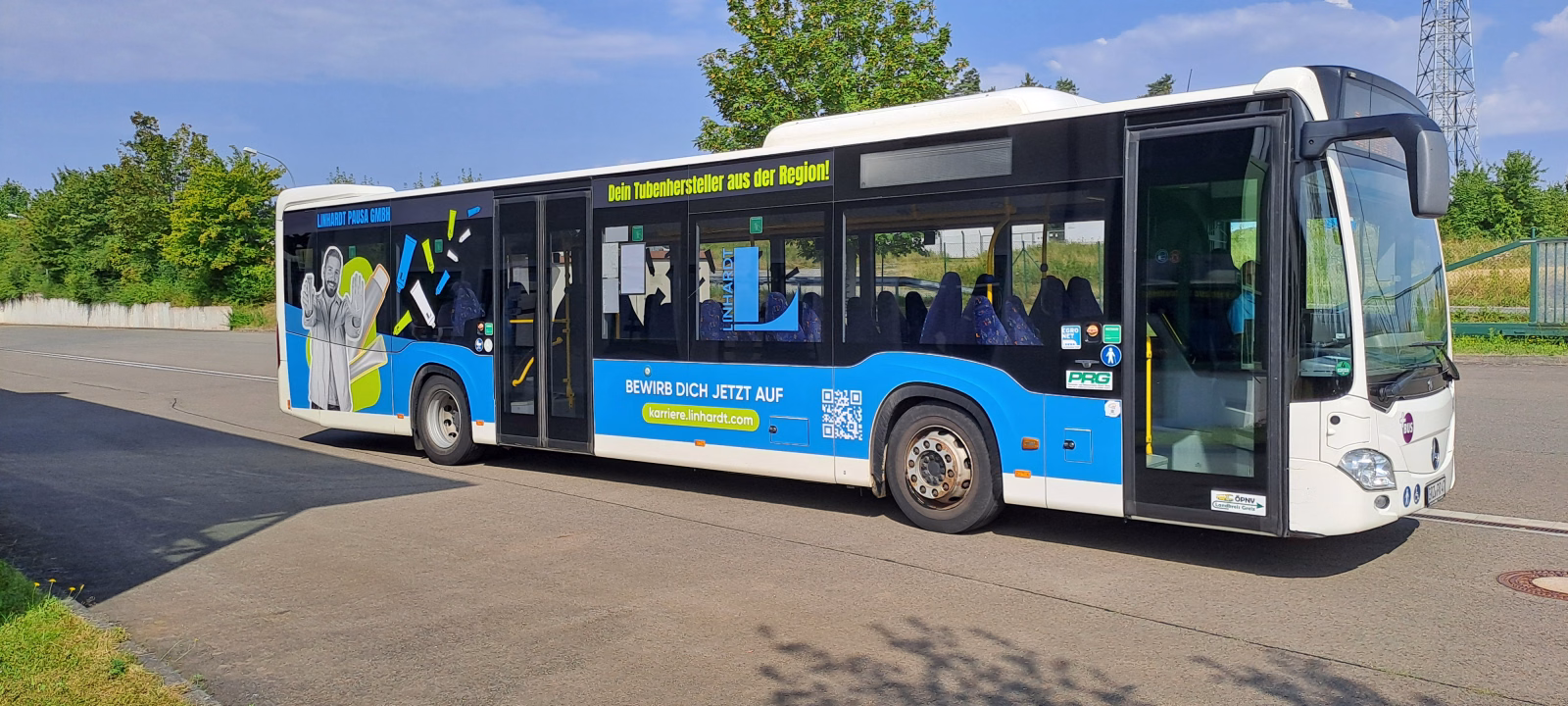 Einstiegsseite eines blauen Stadtbusses mit Werbung der Linhard GmbH