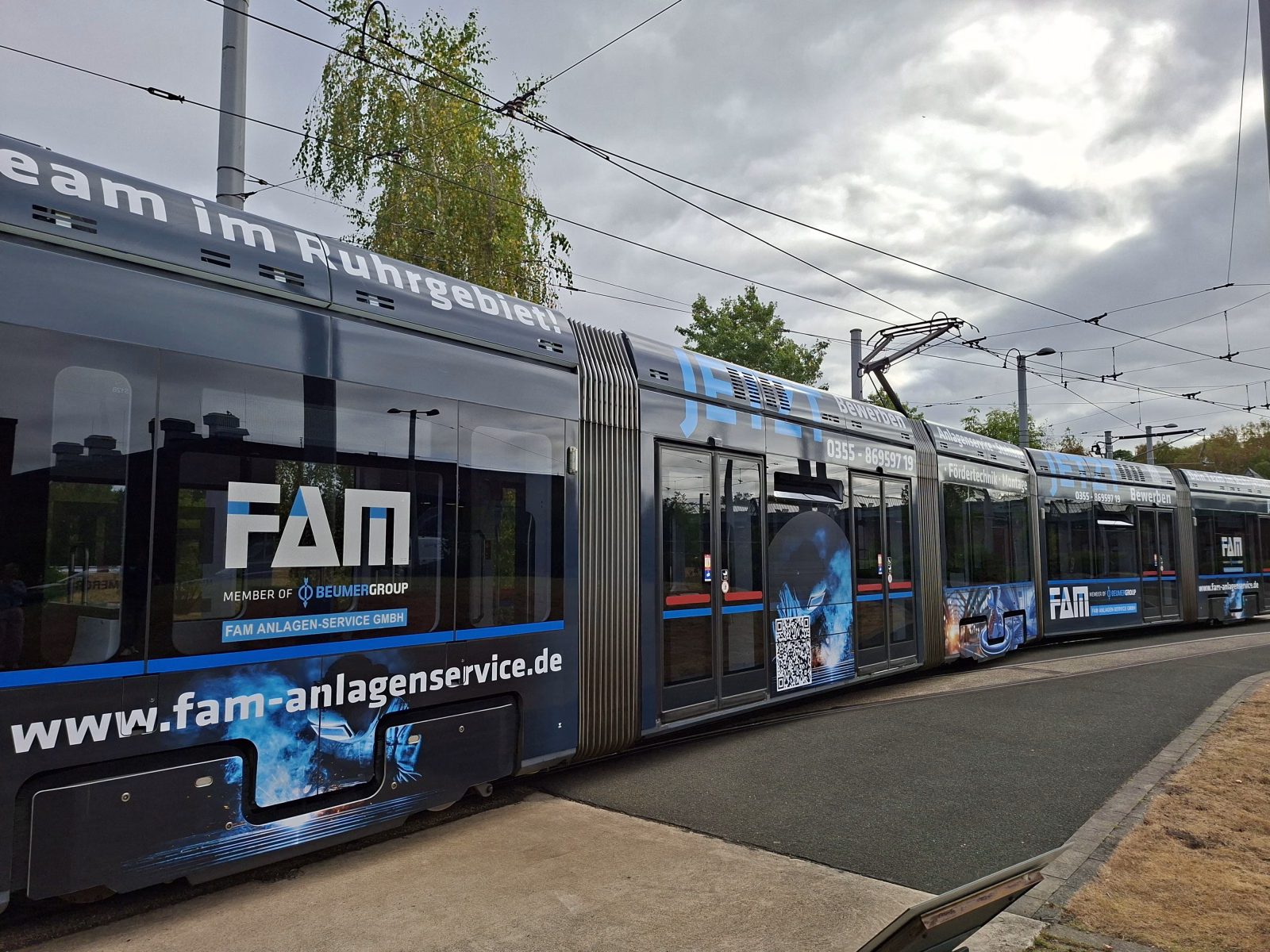 Seitenansicht einer blauen Straßenbahn auf einem Betriebshof mit Werbung der Firma FAM Anlagen