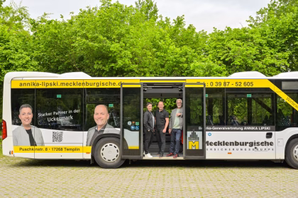 Seitenansicht eines gelben Busses mit geöffneten Türen in dem eine Gruppe von Menschen steht