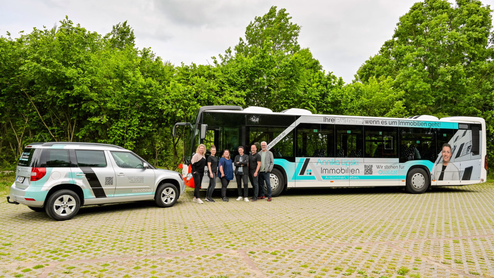 Ein Werbebus und ein dazu passendes Auto stehen auf einem Parkplatz
