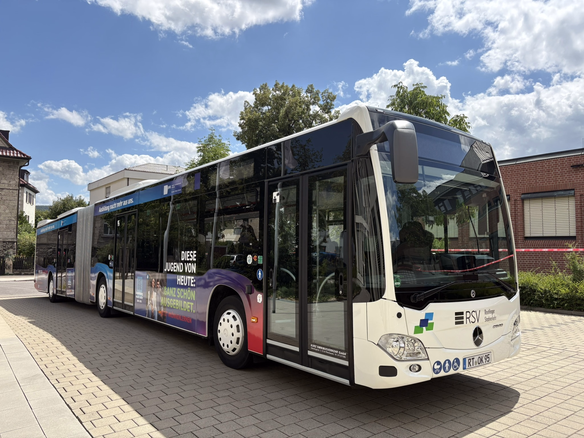 Einstiegsseite eines weißen Gelenkbusses mit Werbung der IHK Reutlingen