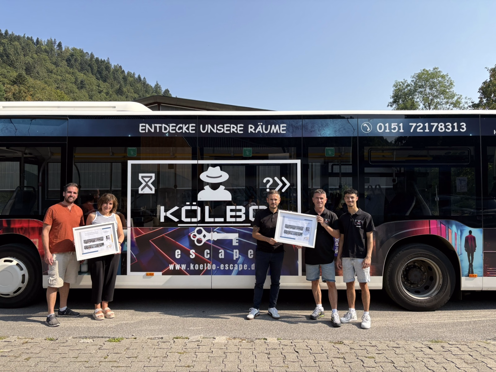 Eine Gruppe von Personen steht vor einem Werbebus von Kölbo Escape