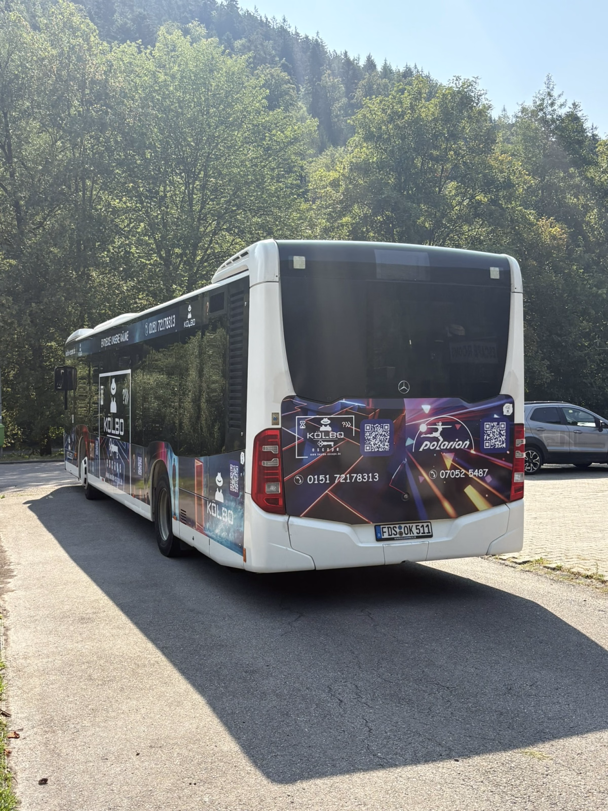 Heckansicht eines weißen Stadtbusses mit Werbung des Kölbo Escape
