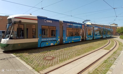 Einstiegsseite einer blauen Straßenbahn mit Werbung der Stadtwerke Augsburg