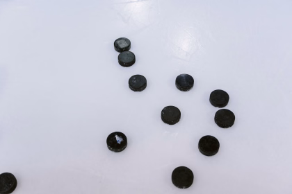 Schwarze Eishockey Pucks liegen auf einer Eisfläche