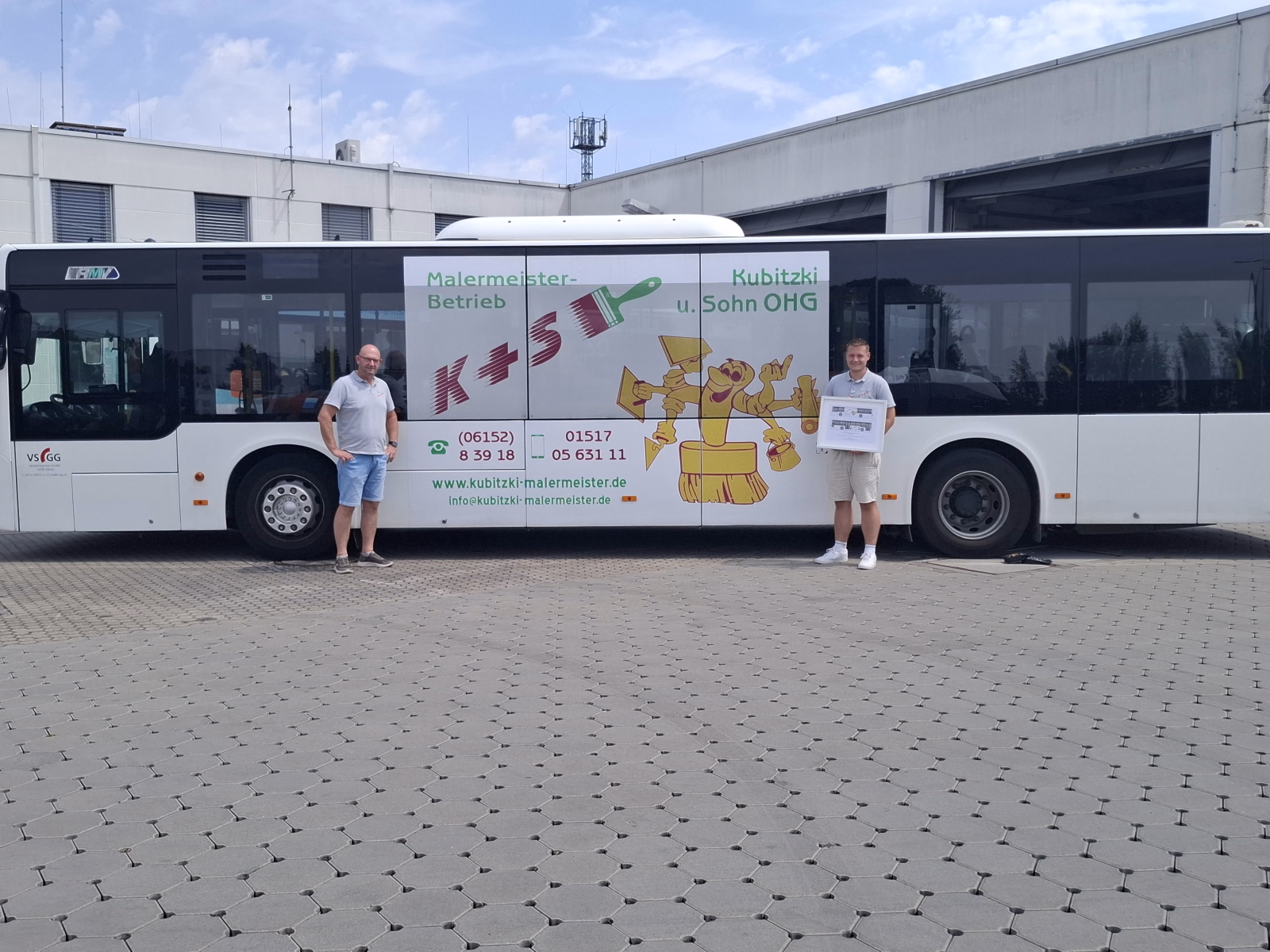 Zwei Personen stehen vor einem weißen Stadtbus mit Werbung des Malermeisters Kubitzkis