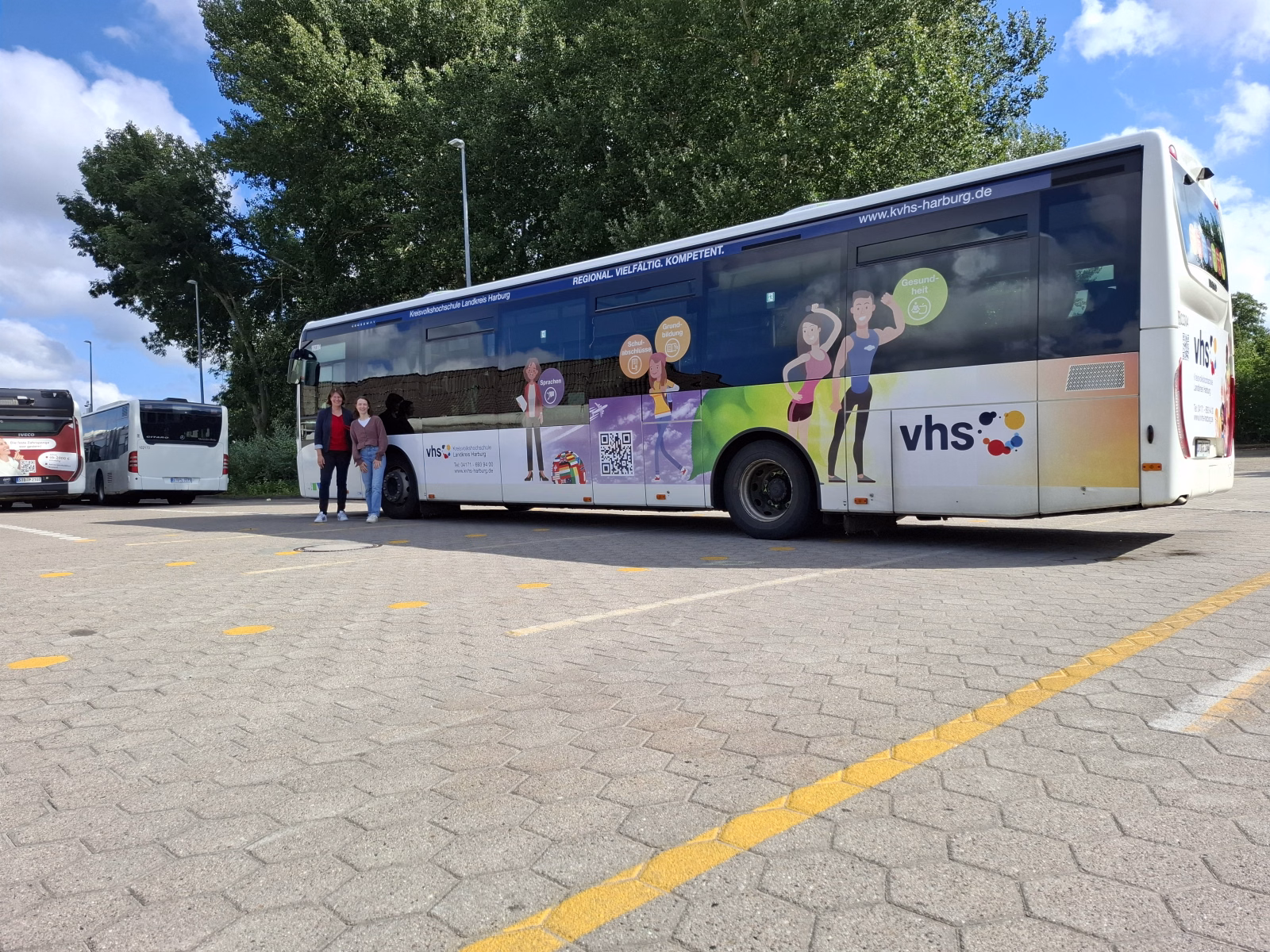 Seitenansicht eines weißen Stadtbusses mit Werbung der Kreisvolkshochschule Harburg