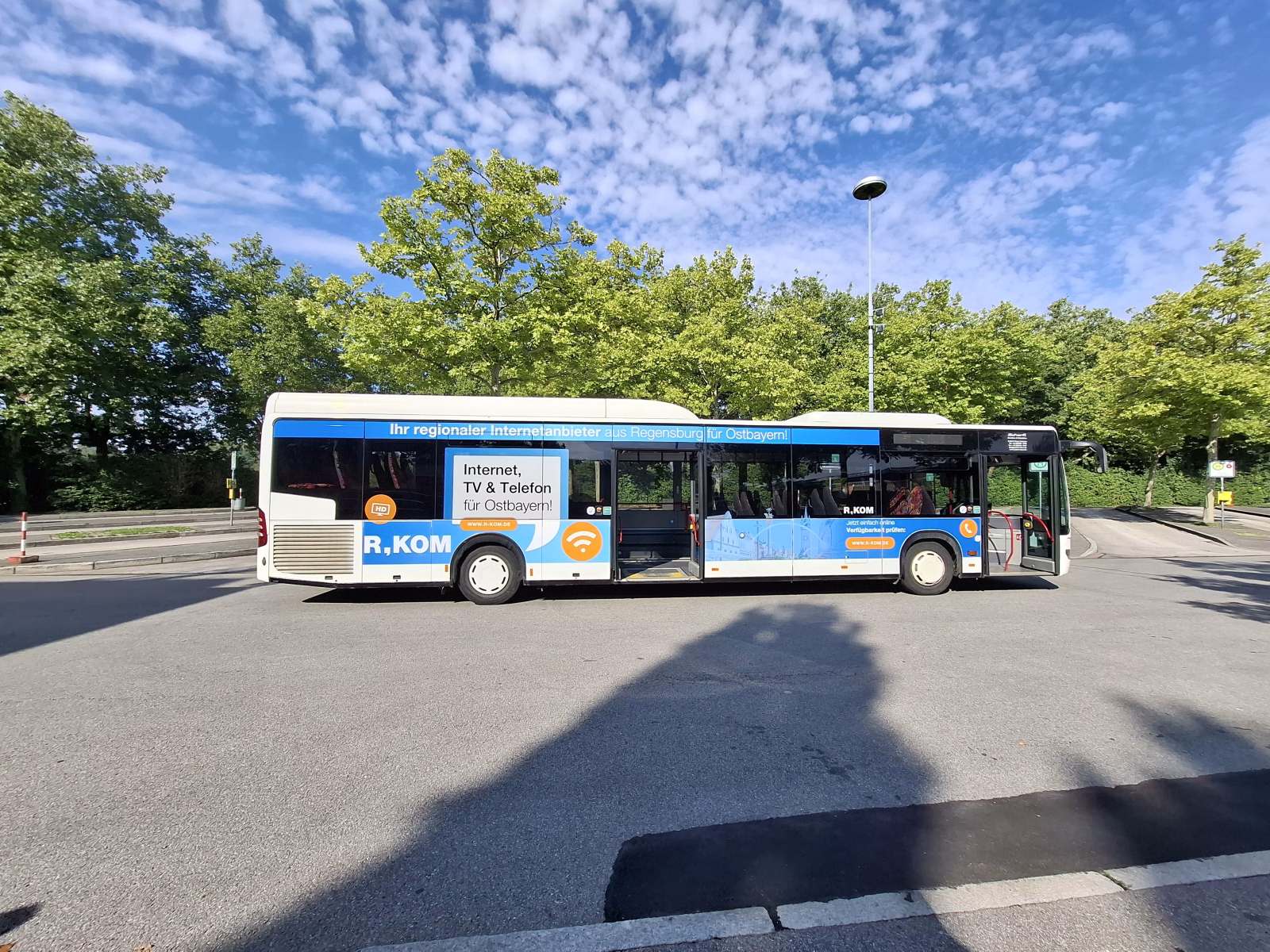Einstiegsseite eines weißen Stadtbusses mit Werbung der R-Kom
