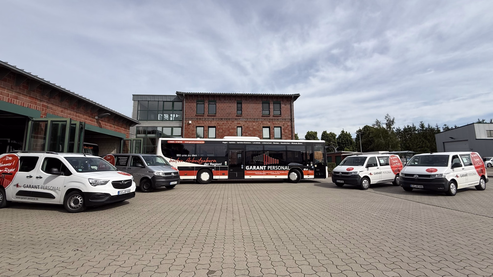 Betriebshof mit einem Werbebus und Firmenfahrzeugen des Garant Personalservices